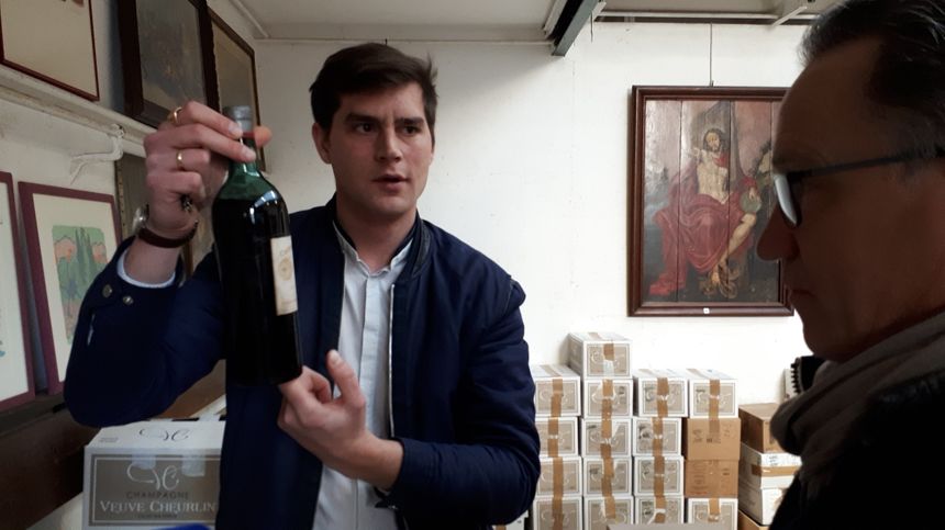 Maxime Guillot, organisateur de la vente, présente le niveau de vin dans la bouteille à un acheteur intéressé par le lot.