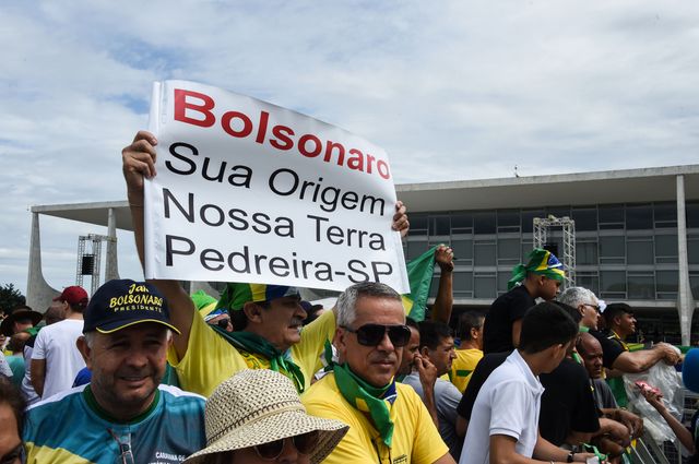 Les partisans brandissent une pancarte où est écrit "Bolsonaro, votre terre, notre terre", alors qu'ils se rassemblent sur la place "Tres Poderes" située en face du palais Planalto à Brasilia.
