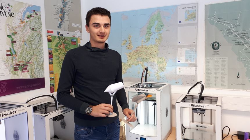 Médhi avec la maquette de sa création, devant l'imprimante 3D qui est en train de la réaliser.