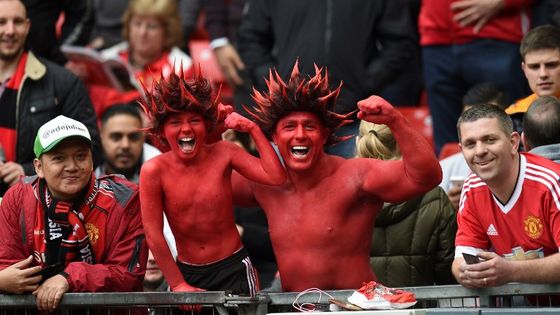 Supporters de Manchester United aux couleurs de leur équipe ©AFP - Oli Scarff