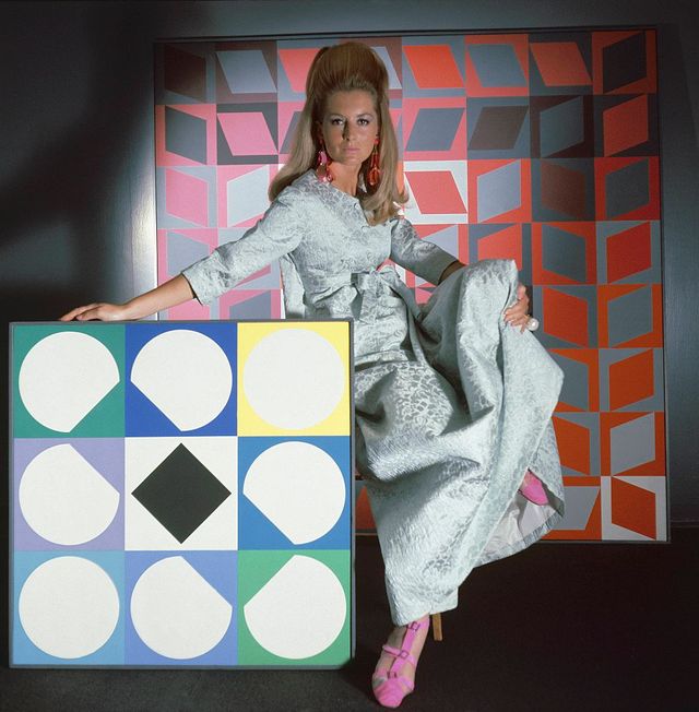 Un mannequin de mode pose sur un décor de toile de Vasarely