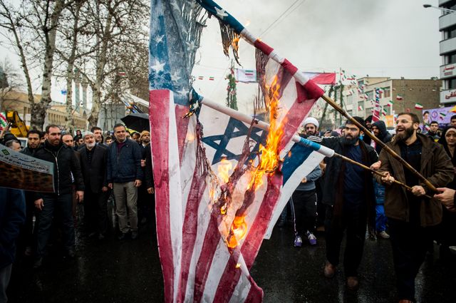 Des Iraniens brûlent des drapeaux américains et israëliens lors des célébrations du 40e anniversaire de la Révolution, le 11 février, à Téhéran