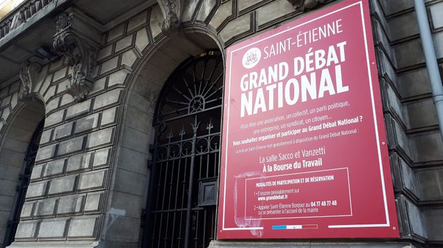 Une annonce pour le grand débat national sur la façade de la bourse du travail à Saint-Étienne.