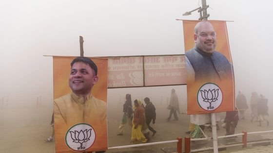 Kumbh Mela, grand rassemblement hindou : pèlerins passant devant les bannières électorales du parti Bharatiya Janata, devant 1 image du président Amit Shah, à droite, à Prayagraj, Uttar Pradesh, Inde, 17 janvier 2019. ©Getty - Prashanth Vishwanathan/Bloomberg via Getty Images