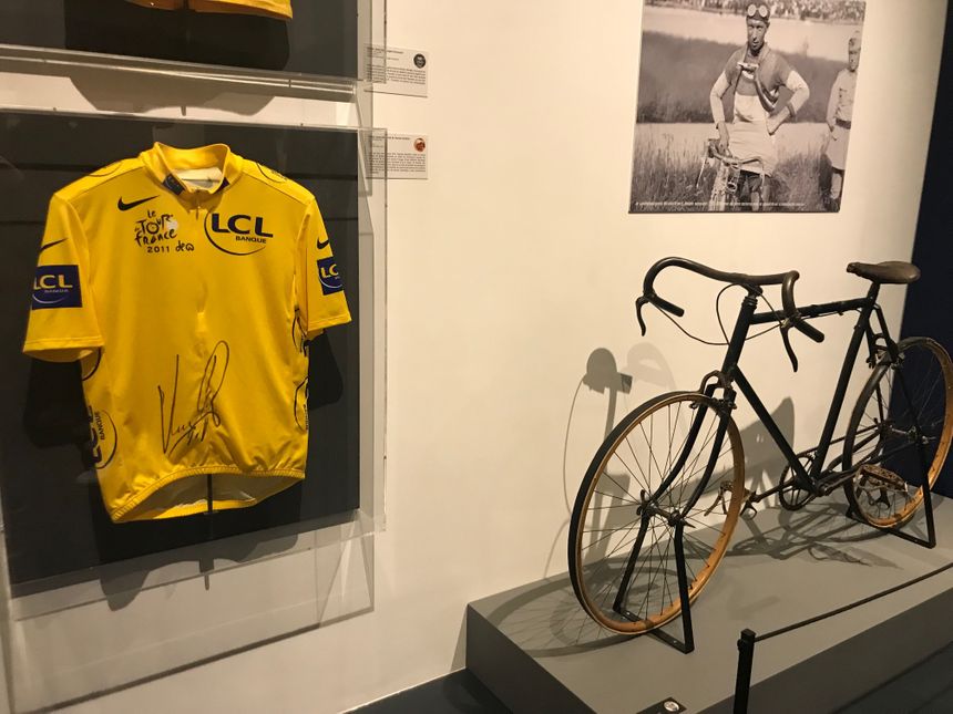 Le maillot jaune porté et signé par Thomas Voeckler près d'un vélo de la fin des années 20