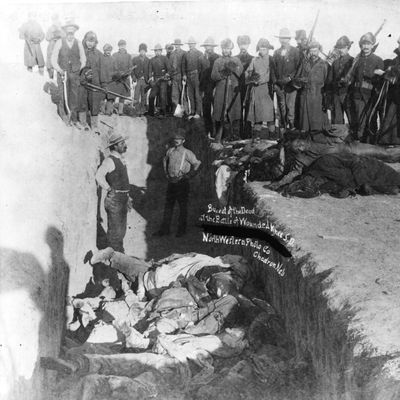 December 1890: Bodies of Sioux Indians being unceremoniously piled into a mass grave hacked into the frozen Dakota soil after the tragedy at Wounded Knee, South Dakota. Soldiers and civilians look on. (Photo by MPI/Getty Images)