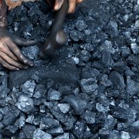 Un ouvrier indien brise le charbon en morceaux. En Inde, le charbon fournit 75,9 % du courant électrique.