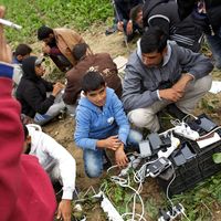 Des migrants chargent leurs smartphones alors qu'ils attendent à quelques mètres de la frontière croate, après avoir parcouru les derniers kilomètres entre Serbie et Croatie à Sid, en Serbie (2015).