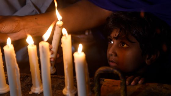 Un enfant chrétien devant des bougies allumées en hommage aux victimes des explosions au Sri-Lanka ©AFP - RIZWAN TABASSUM