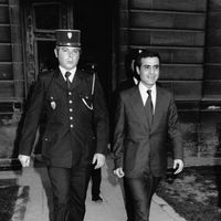 Pierre Goldman à côté d'un gendarme à son procès le 4 mai 1976 à Amiens