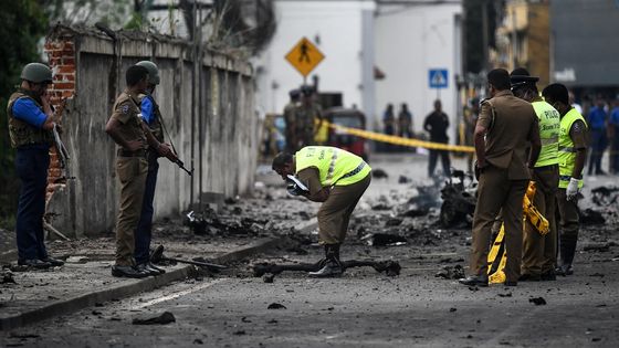 Un agent de sécurité sri-lankais inspecte les débris d'une voiture explosée peu après la vague d'explosions qui a frappé des églises et des hôtels de luxe le 22 avril à Colombo. ©AFP - Jewel SAMAD