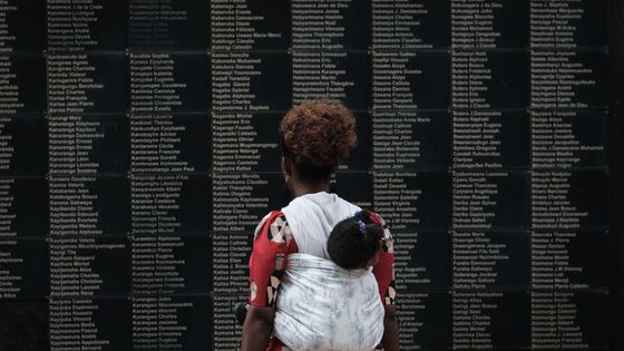 Une femme portant son enfant regarde le mur des victimes au Mémorial du génocide de Kigali le 8 avril 2019 . La veille, le Rwanda a commencé 100 jours de deuil pour plus de 800 000 personnes massacrées par le génocide qui a choqué le monde. ©AFP - YASUYOSHI CHIBA / AFP