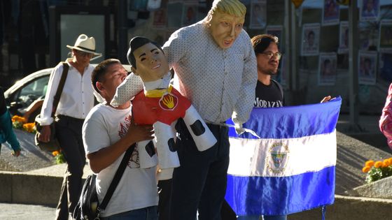 MEXICO CITY, MEXICO - OCTOBER 23: A man holds a mask of Donald Trump during the Mexicans meet outside the United States Embassy to plan a welcoming and gather donations for the migrant caravan coming from Honduras on October 23, 2018 ©Getty - Photo by Carlos Tischler/Getty Images
