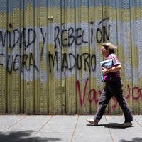 Une femme marchant devant un graffiti de l'opposition à Caracas