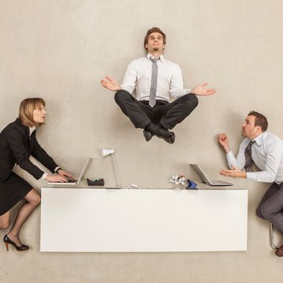 Un employé médite pleinement sur ce qu'il est en train de faire à son travail pendant que les autres travaillent sans ménagement