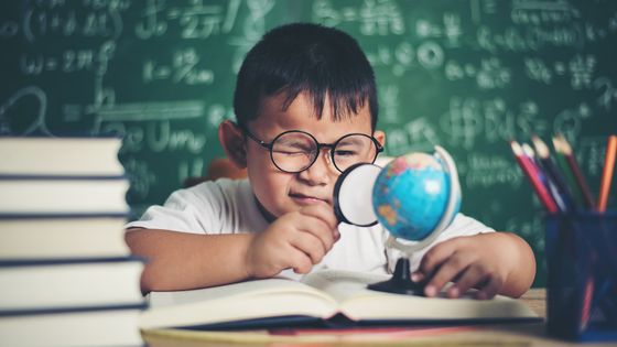 Un jeune garçon qui étudie, loupe à la main, une petite mappemonde ©Getty - Prakasit Khuansuwan / EyeEm