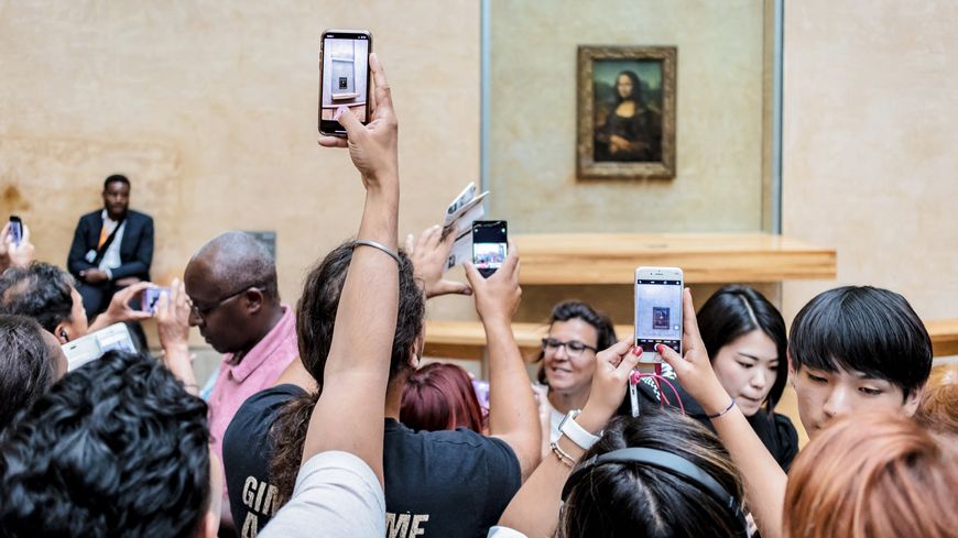 Plusieurs visiteurs photographient le tableau ou font des selfies devant La Joconde, Musée du Louvre. 26 août 2018