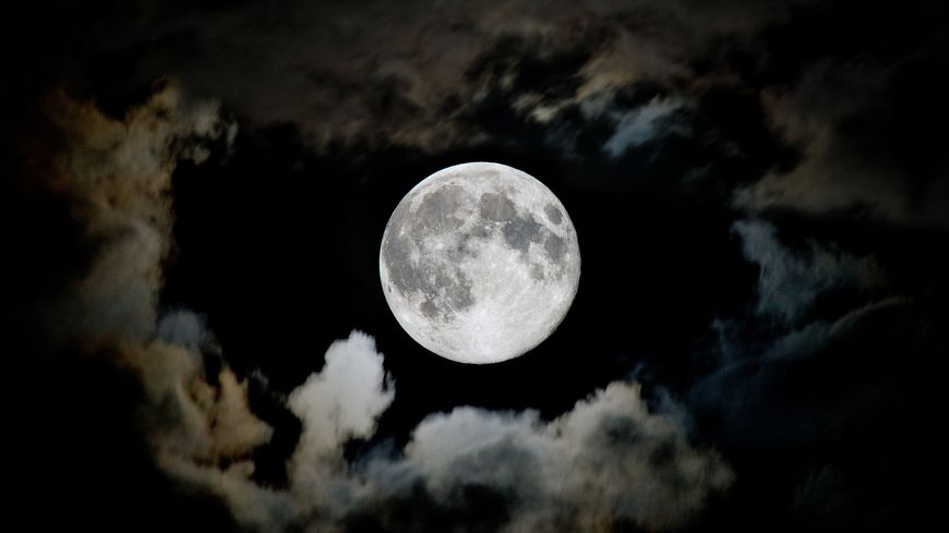La lune, encadrée de nuages.