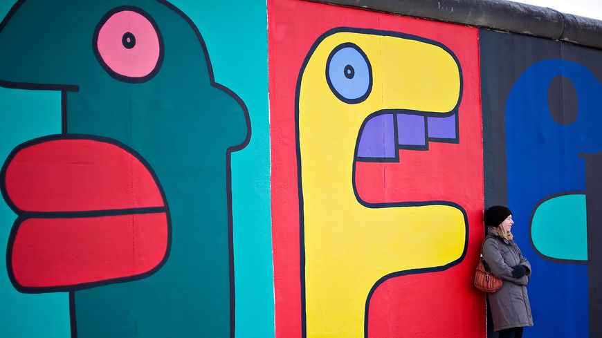 Une touriste pose devant une des oeuvres de Thierry Noir, sur la East Side Gallery du Mur de Berlin.