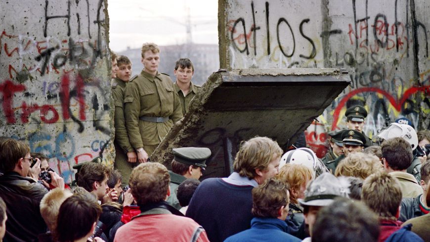 Des soldats est-allemands abbattent une section du mur de Berlin.