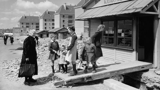 Des enfants et une "mamie" devant le magasin provisoire d'une boulangerie, en mai 1949, à Saint-Lô en complète reconstruction à cause des bombardements de la guerre 1939/1945. ©AFP - Staff