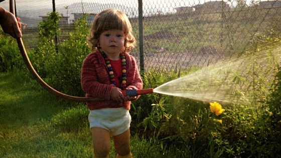 Young girl watering the garden with a hosepipe ©Getty - sparwasser