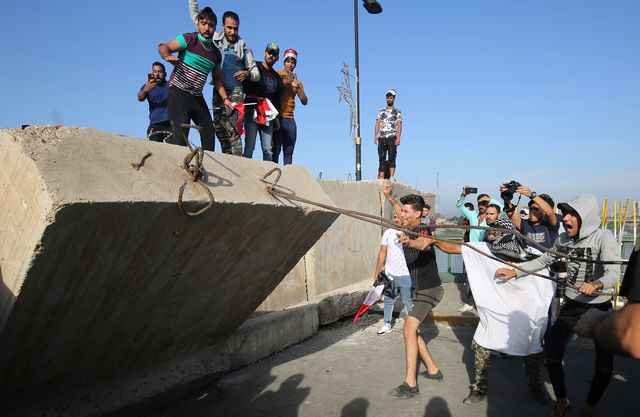 Des manifestants tentent de faire tomber un mur de la Zone Verte de Bagdad qui protège les bâtiments gouvernementaux le 25 octobre