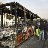 Des Iraniens face à l'épave d'un bus incendié par des manifestants dans la ville centrale d'Ispahan le 17 novembre 2019.