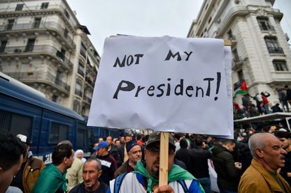 Un manifestant à Alger brandit une pancarte "Pas mon président" après l'élection contestée d'Abdelmadjid Tebboune (13/12/2019) Un manifestant à Alger brandit une pancarte "Pas mon président" après l'élection contestée d'Abdelmadjid Tebboune (13/12/2019)