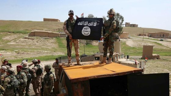 Des soldats irakiens tiennent un drapeau de Daech qu'ils viennent de récupérer après une victoire à Kharbardan, le 9 avril 2016 ©AFP - . SAFIN HAMED