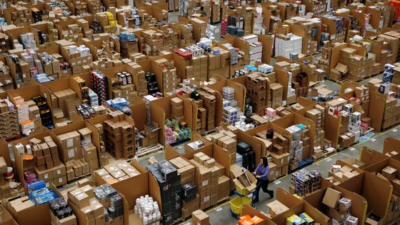Les travailleurs marchent le long des allées de marchandises stockées à l'intérieur d'un centre de distribution Amazon.co.uk à Hemel Hempstead, au nord de Londres. ©AFP - Adrian