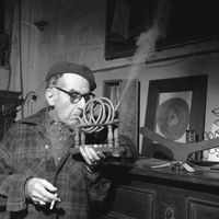 Man Ray faisant la démonstration de son objet d'art intitulé "Smoking Device"