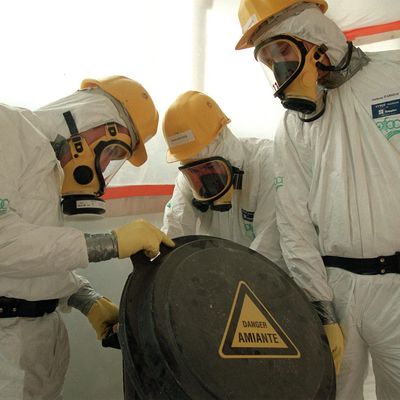 Des employés d'une entreprise de décontamination, revêtus de combinaisons spéciales