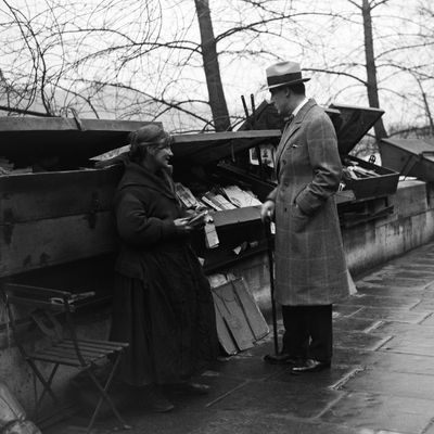 L'écrivain Jacques de Lacretelle avec une bouquiniste sur les quais de Seine, à Paris en 1928.