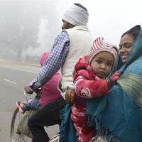 Famille indienne à bicyclette, chaudement vêtue en raison de températures anormalement froides. Le 30 décember 2019 à New Delhi, Inde.