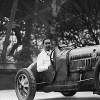 L'écrivain français Paul Morand (1888-1976) au volant d'une voiture de course sous la Tour Eiffel. (photo non datée)