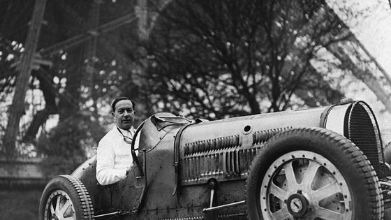 L'écrivain français Paul Morand (1888-1976) au volant d'une voiture de course sous la Tour Eiffel. (photo non datée) ©AFP - STF