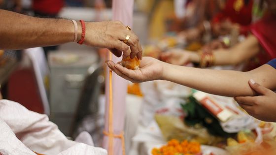 Main offrant de la nourriture à une autre personne dans un temple ©Getty - Sandeep Raj / EyeEm