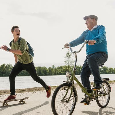 Jeune homme en skateboard qui accompagne un vieil homme en vélo