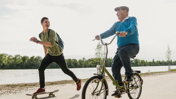 Jeune homme en skateboard qui accompagne un vieil homme en vélo ©Getty - © Westend61