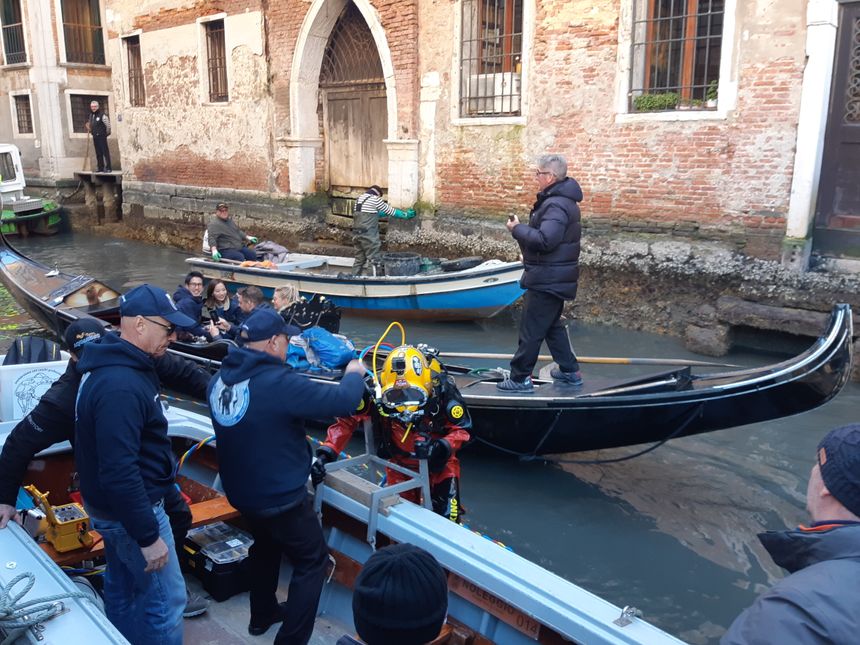 Ferruccio, le gondolier sous-marin, sort de l'eau accueilli par son collègue Alessandro Zuffi, à l'origine de l'initiative, sous les yeux de touristes en gondole