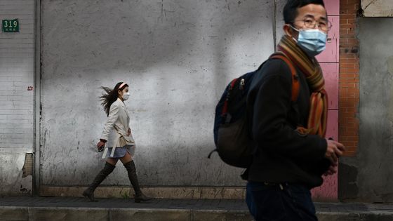 Passants masqués dans une rue de Shanghai, lundi 17 février 2020, alors que la Chine combat toujours l’épidémie de coronavirus. ©AFP - Noel Celis / AFP