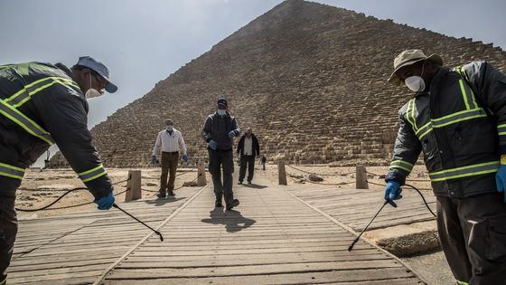 Au pied de la pyramide de Gizeh, près du Caire, des égyptiens désinfectent les lieux dans le cadre de la lutte contre le coronavirus. ©AFP - Khaled DESOUKI / AFP