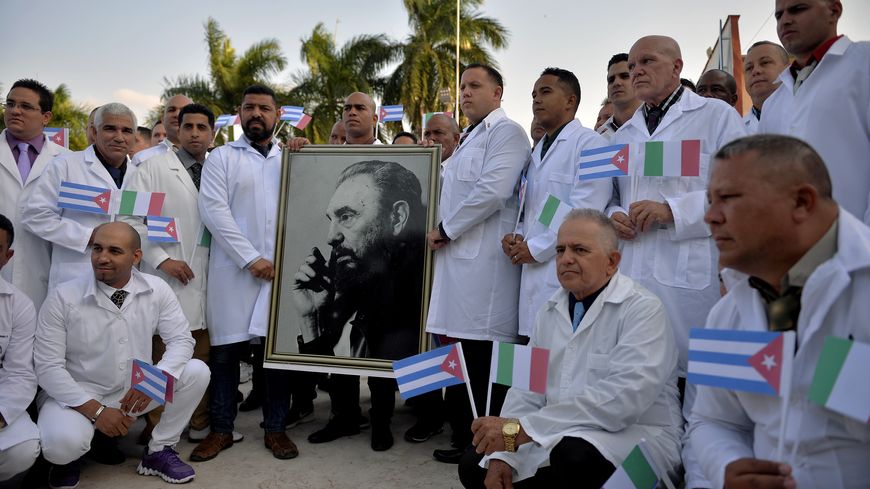 Des médecins de la brigade médicale internationale Henry Reeve de CubaInternational Medical Brigade posent avec un portait de Fidel CastroFidel Castro, à La Havane, le 21 mars 2020 avant de partir lutter contre le coronavirus en Italie.