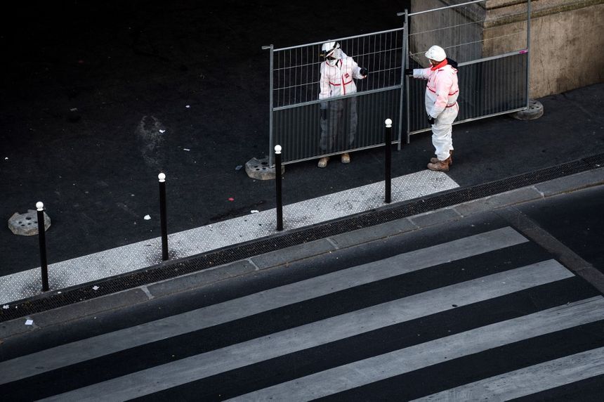 Les travailleurs en tenue de protection sont à pied d'œuvre pour installer des barrières pour un site prioritaire le 23 mars 2020 à Paris, alors que le pays est sous confinement pour arrêter la propagation du Covid-19