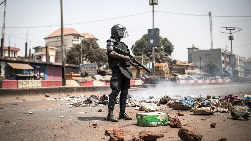 Un policier se tient le long de l'"axe de la démocratie" alors que des manifestations ont éclaté à Conakry le 29 février 2020. Le 28 février 2020, le président guinéen Alpha Condé a annoncé un "léger report" du référendum du 1er mars sur l'adoption d