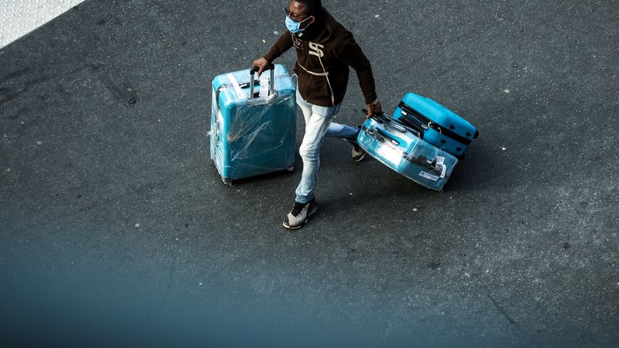Un homme circule dans les rues de Paris, valises à la main, quelques heures avant le confinement.