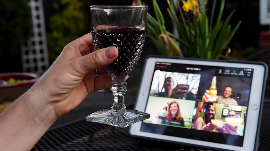 Une femme lève son verre et applaudit avec des amis lors d'un happy hour virtuel au milieu de la crise du coronavirus (Covid-19) le 8 avril 2020 à Arlington, en Virginie
