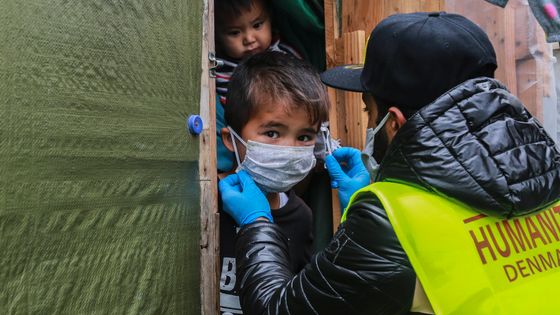 Un membre de l'ONG "Team Humanity" partage des masques protecteurs faits à la main aux migrants et aux réfugiés dans le camp de Moria sur l'île de Lesbos le 28 mars 2020 ©AFP - Manolis LAGOUTARIS
