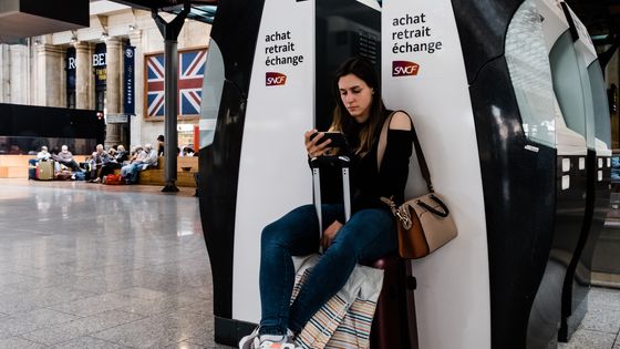 Une jeune femme assise sur sa valise attend son train, à Paris, le 23 avril. ©AFP - Karine Pierre / Hans Lucas